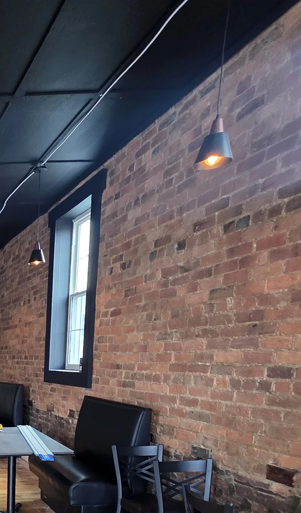Exposed brick wall, window and banquette seating