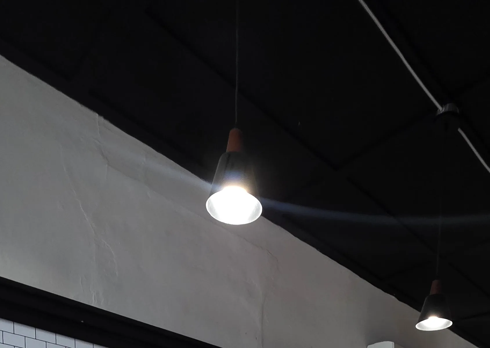 A filament pendant lit against the black ceiling at STEAMED