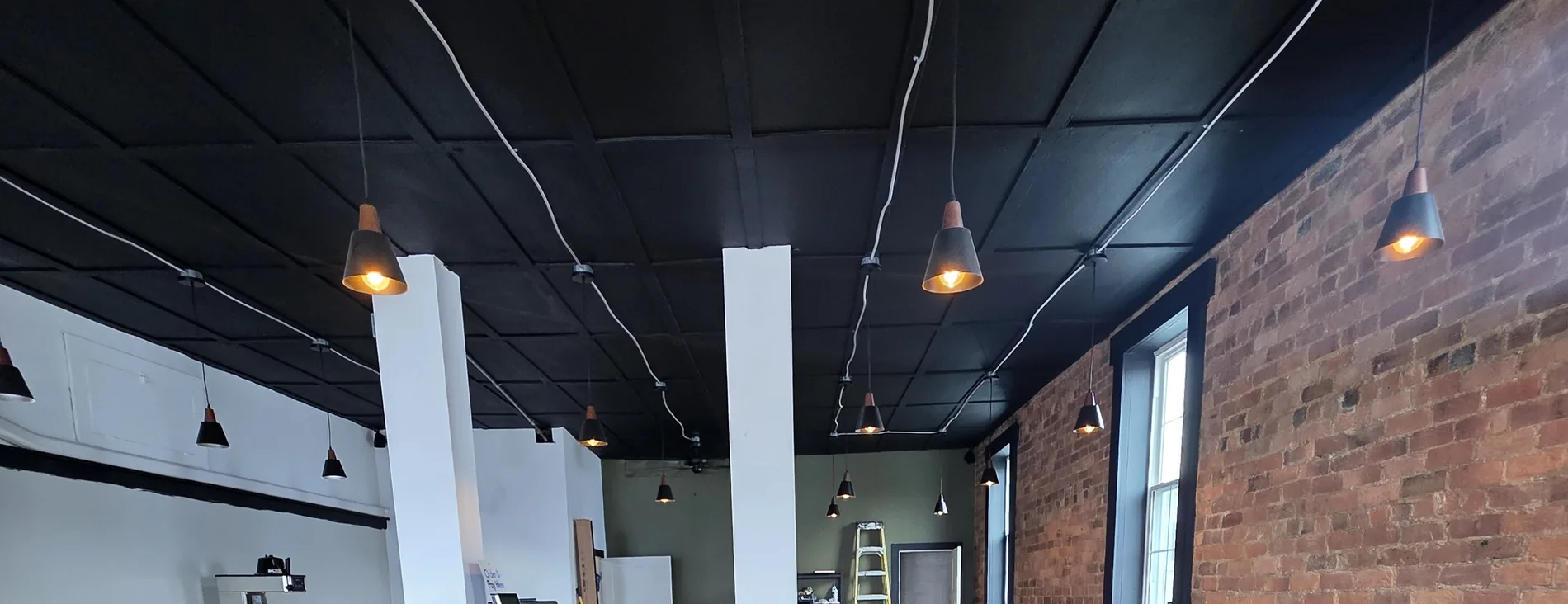 The dining room at STEAMED — pendants, brick and black ceiling